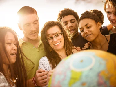 Junge Menschen blicken gemeinsam auf einen Globus
